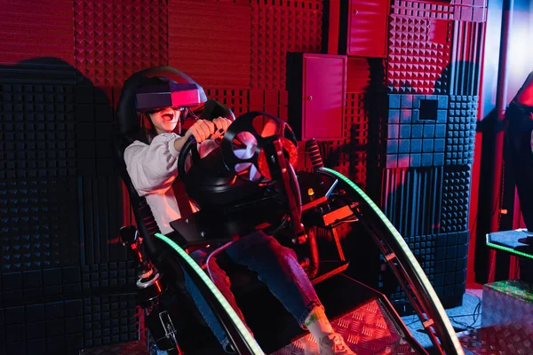 Adolescent excité fille dans vr casque de jeu sur simulateur de course automobile — Photo de stock
