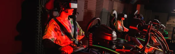 Erstaunt Gamer Rennen auf Auto-Simulator in der Nähe verschwommene Freunde, Banner — Stockfoto