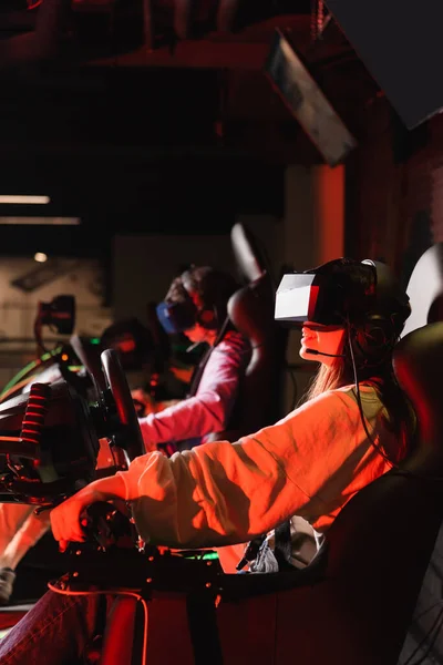 Teenage friends in vr headsets gaming on car racing simulators — Stock Photo