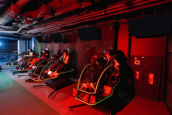 Amigos adolescentes em realidade virtual headsets jogos em simuladores de corrida — Fotografia de Stock
