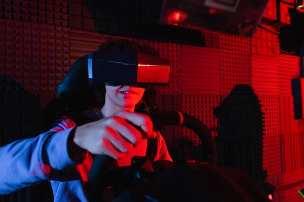 Concentrated guy in vr headset racing on car simulator — Stock Photo