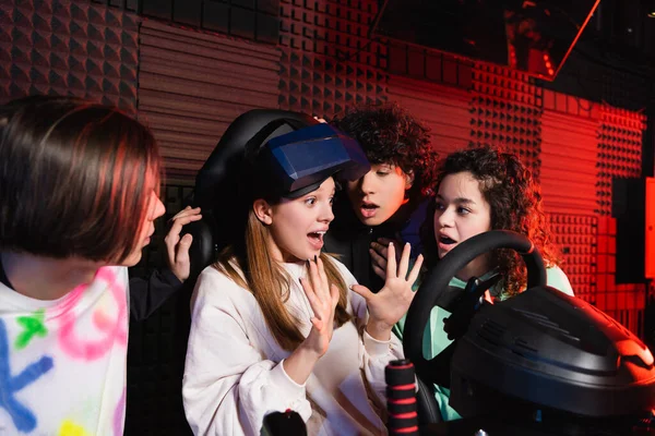 Verängstigtes Mädchen gestikuliert im Auto-Simulator in der Nähe von Freunden — Stockfoto