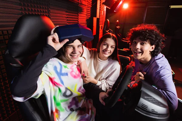 Heureux joueurs souriant à la caméra près du simulateur de course automobile — Photo de stock