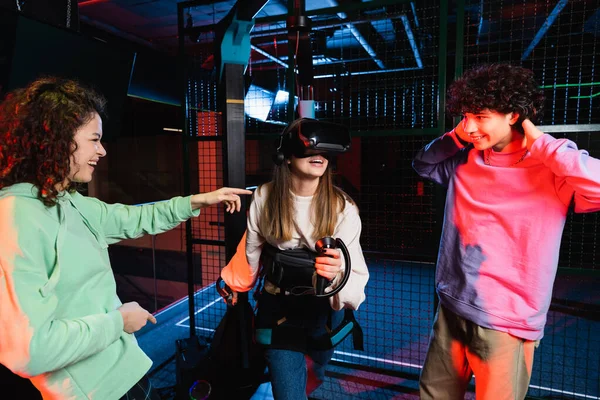 Menina americana africana alegre apontando para amigo jogos na zona vr — Fotografia de Stock