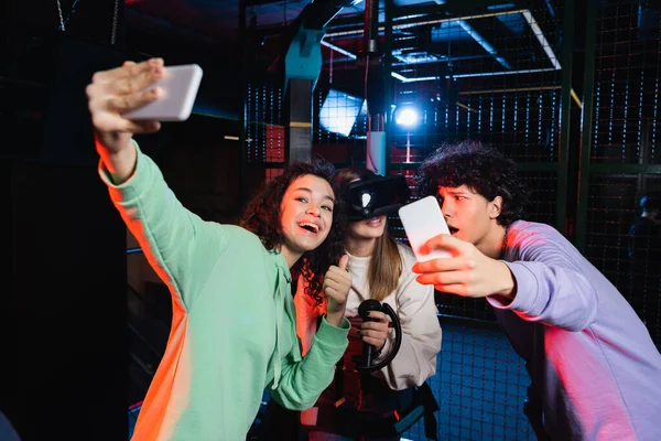 Cheerful interracial teenagers taking selfie with friend in vr headset — Stock Photo