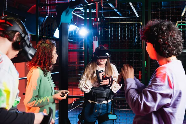 Emocionados juegos de chicas adolescentes en auriculares vr cerca de amigos multiétnicos - foto de stock