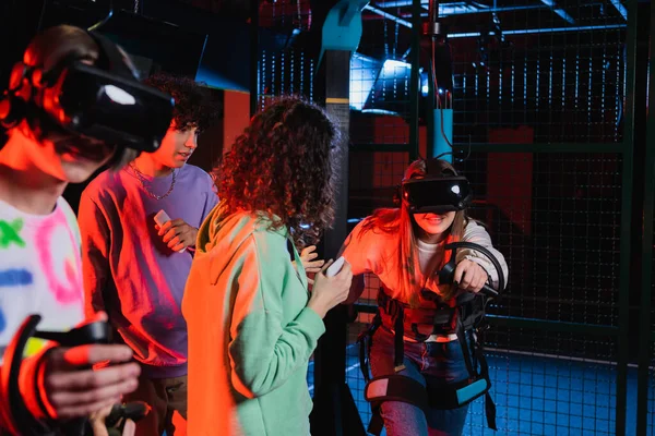 Teenage girl in headset gaming in vr play zone near interracial friends — Stock Photo