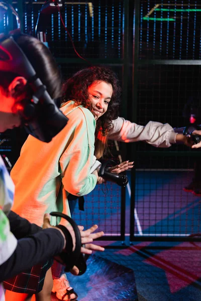 African american girl smiling near friend gaming in vr headset — Stock Photo