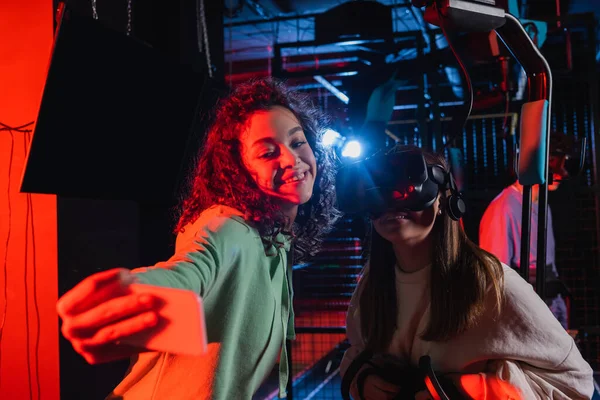 Menina americana africana alegre tomando selfie com amigo no fone de ouvido vr — Fotografia de Stock