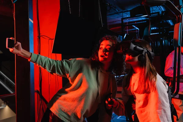 Astonished african american teenage girl taking selfie with friend in vr headset — Stock Photo