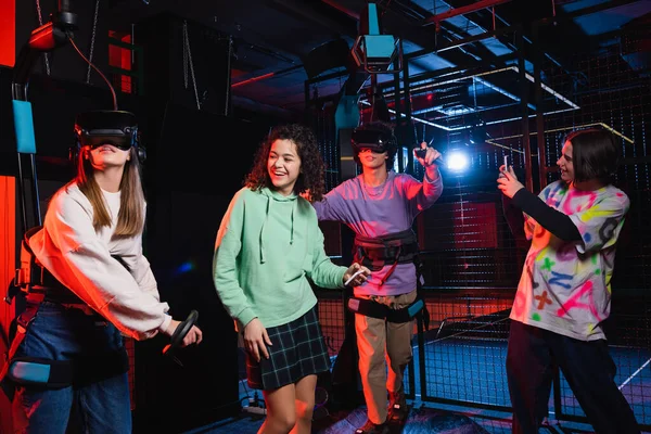 Teenage boy taking photo of cheerful interracial friends in vr game zone — Stock Photo