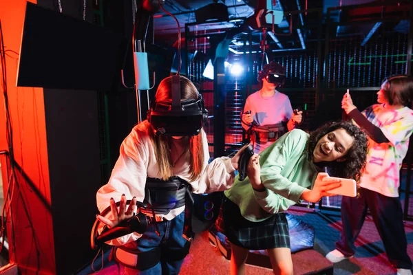 Excited african american girl taking picture of friend in vr headset — Stock Photo