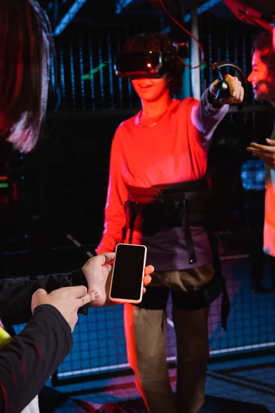 Adolescente in possesso di smartphone con schermo bianco vicino agli amici interrazziali nella zona vr — Foto stock