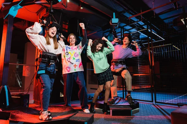 Excited multicultural teenagers showing rejoice gesture in vr game room — Stock Photo