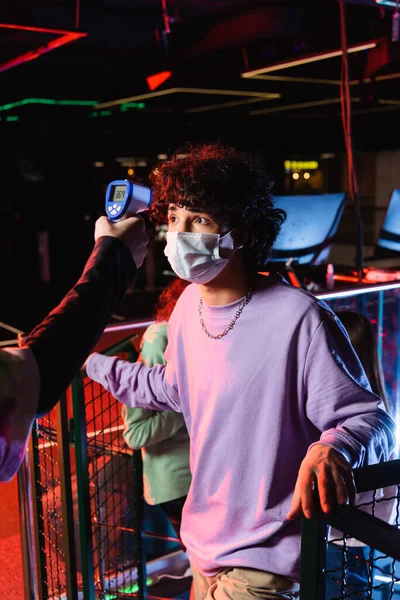 Adolescent garçon dans masque médical près contrôleur avec pyromètre — Photo de stock