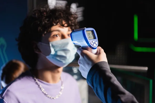 Selective focus of pyrometer in hand of controller near boy in safety mask — Stock Photo
