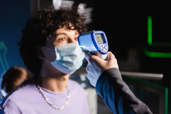 Messa a fuoco selettiva del pirometro in mano del controller vicino ragazzo in maschera di sicurezza — Foto stock