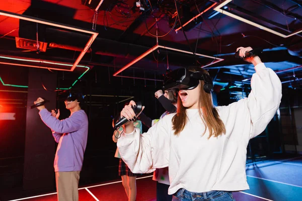 Menina animado em jogos vr fone de ouvido perto de amigos na sala de jogos — Fotografia de Stock