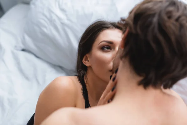 Junge Frau küsst verschwommenen Freund auf Bett — Stockfoto
