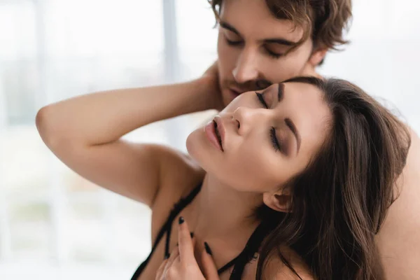 Sexy woman with closed eyes touching blurred boyfriend — Stock Photo