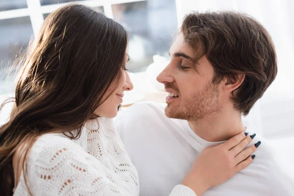 Vista lateral de la mujer sonriente abrazando novio en casa - foto de stock