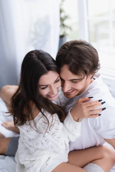 Sonriente joven pareja abrazándose en el dormitorio - foto de stock