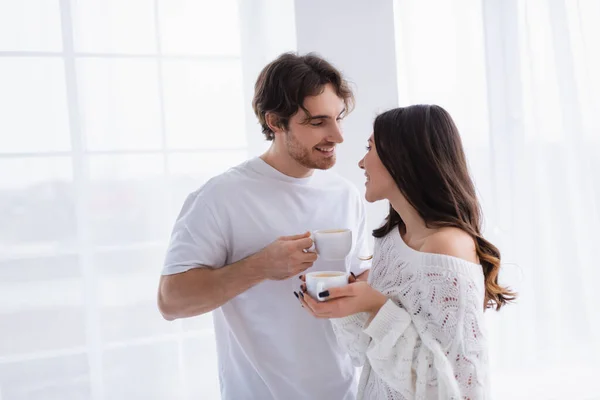 Улыбающийся мужчина с кофе смотрит на девушку в свитере — стоковое фото