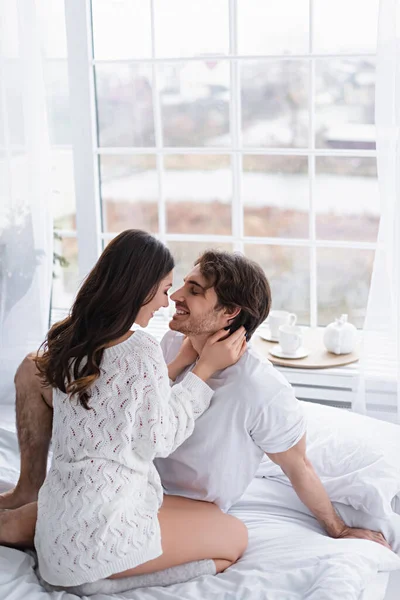 Mujer sonriente en suéter abrazando joven novio en el dormitorio - foto de stock