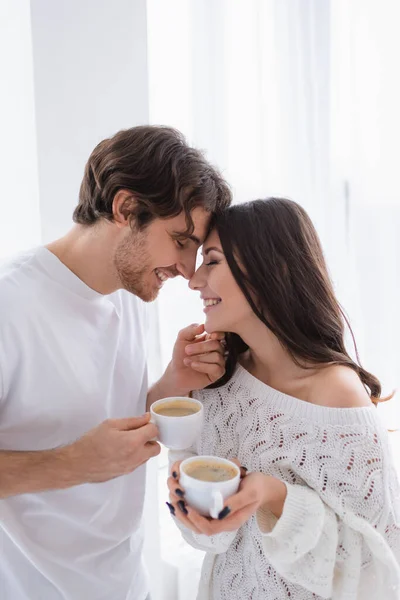 Smiling couple with coffee standing at home — Stock Photo