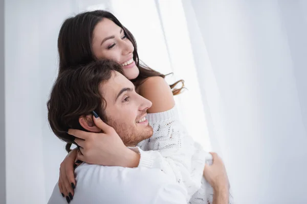 Улыбающийся мужчина обнимает девушку дома — стоковое фото