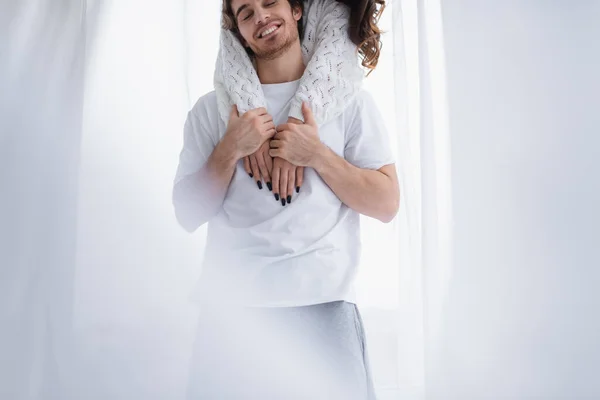 Mulher abraçando namorado perto de cortina em casa — Fotografia de Stock