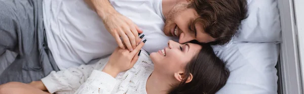 Vista dall'alto della coppia sorridente sdraiata sul letto, banner — Foto stock