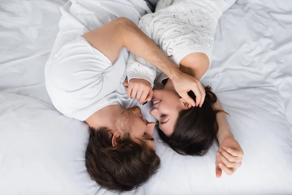 Vue de dessus du couple souriant avec les yeux fermés embrassant à la maison — Photo de stock