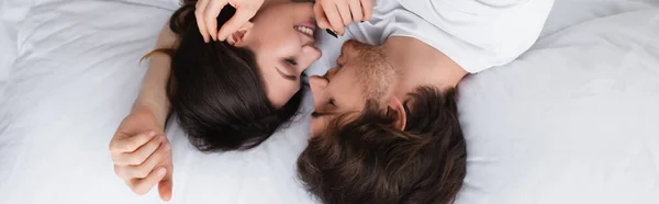 Vista superior de la pareja sonriente acostada en la ropa de cama blanca, pancarta - foto de stock