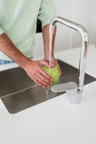 Vista cortada do homem lavando alface fresca na cozinha — Fotografia de Stock