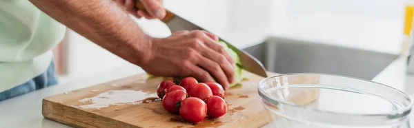 Vue recadrée de l'homme coupant des tomates cerises fraîches près du bol, bannière — Photo de stock