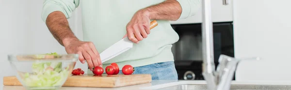 Vista cortada do homem cortando tomates cereja em primeiro plano borrado, banner — Fotografia de Stock