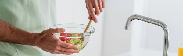 Vista recortada del hombre mezclando ensalada de verduras frescas en un tazón, pancarta - foto de stock