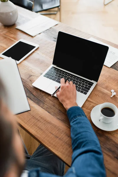 Vista parziale di libero professionista che lavora a computer portatile vicino a targa digitale e tazza di caffè — Foto stock