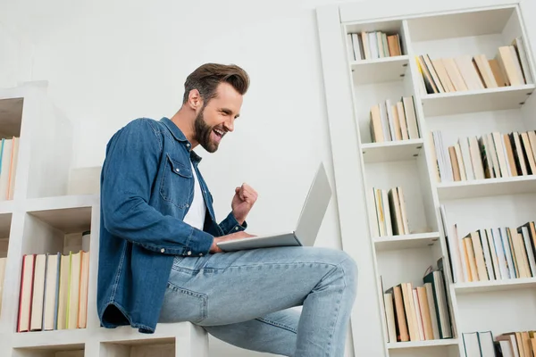 Aufgeregter Mann zeigt Yah-Geste beim Blick auf Laptop — Stockfoto