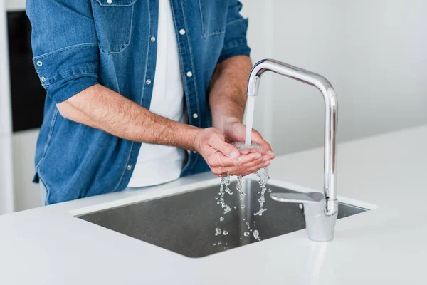 Teilbild eines Mannes im Jeanshemd, der sich zu Hause die Hände wäscht — Stockfoto