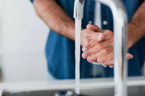 Обрізаний вид розмитого чоловіка, що миє руки з милом — стокове фото