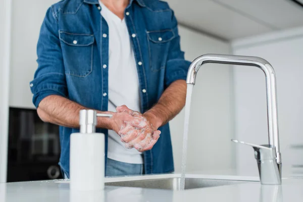 Vista recortada del hombre lavándose las manos con jabón en casa - foto de stock