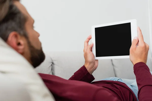 Hombre sosteniendo tableta digital con pantalla en blanco mientras descansa en casa - foto de stock