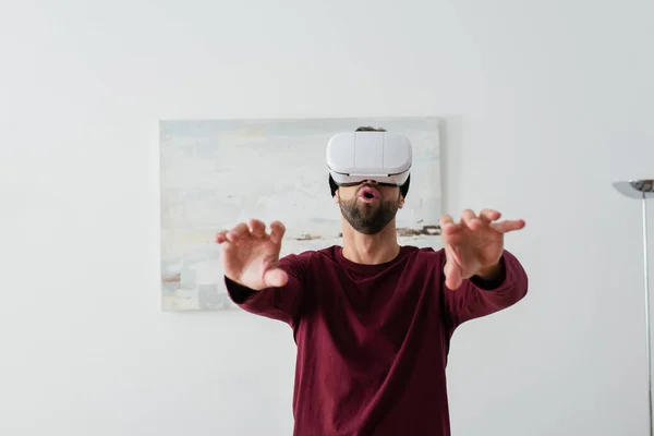 Удивленный мужчина жестикулирует во время игры в гарнитуре VR — стоковое фото