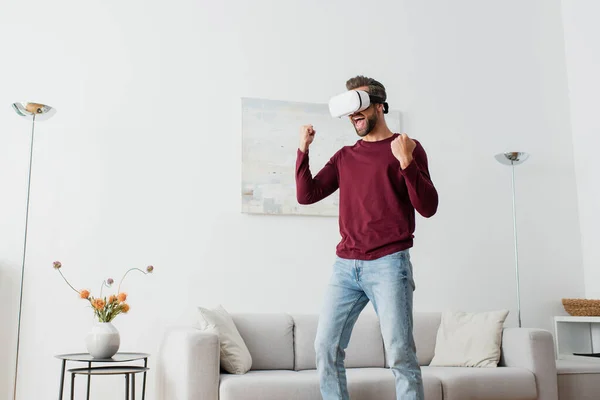 Uomo eccitato in auricolare vr gridando mentre mostra gesto trionfo — Foto stock