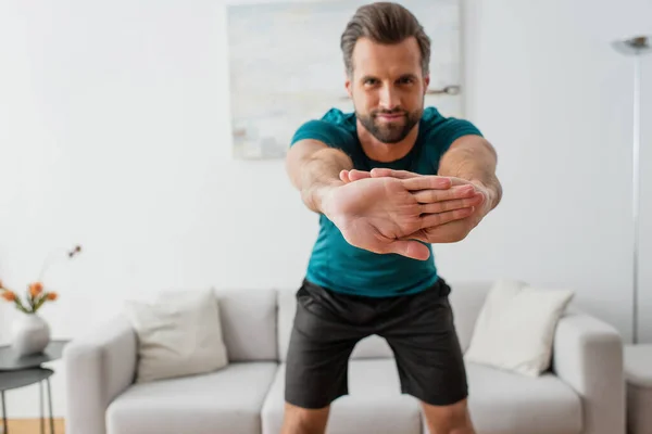 Blurred sportsman looking at camera while warming up at home — Stock Photo