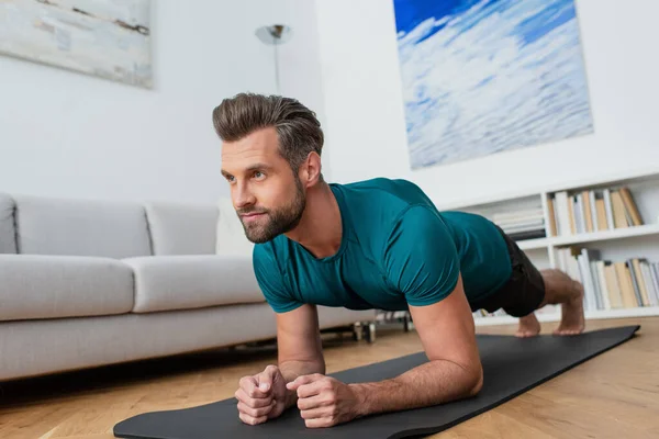 Hombre descalzo practicando yoga en postura de tablón en casa - foto de stock