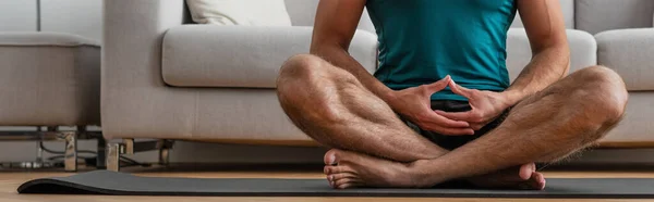 Vista parcial del hombre descalzo practicando yoga en pose de loto, bandera - foto de stock
