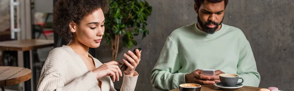 Africano mulher americana usando smartphone perto de namorado e café no café, banner — Fotografia de Stock